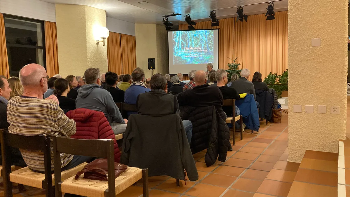 Eine Frau referiert vor den Zuhörenden im Saal.